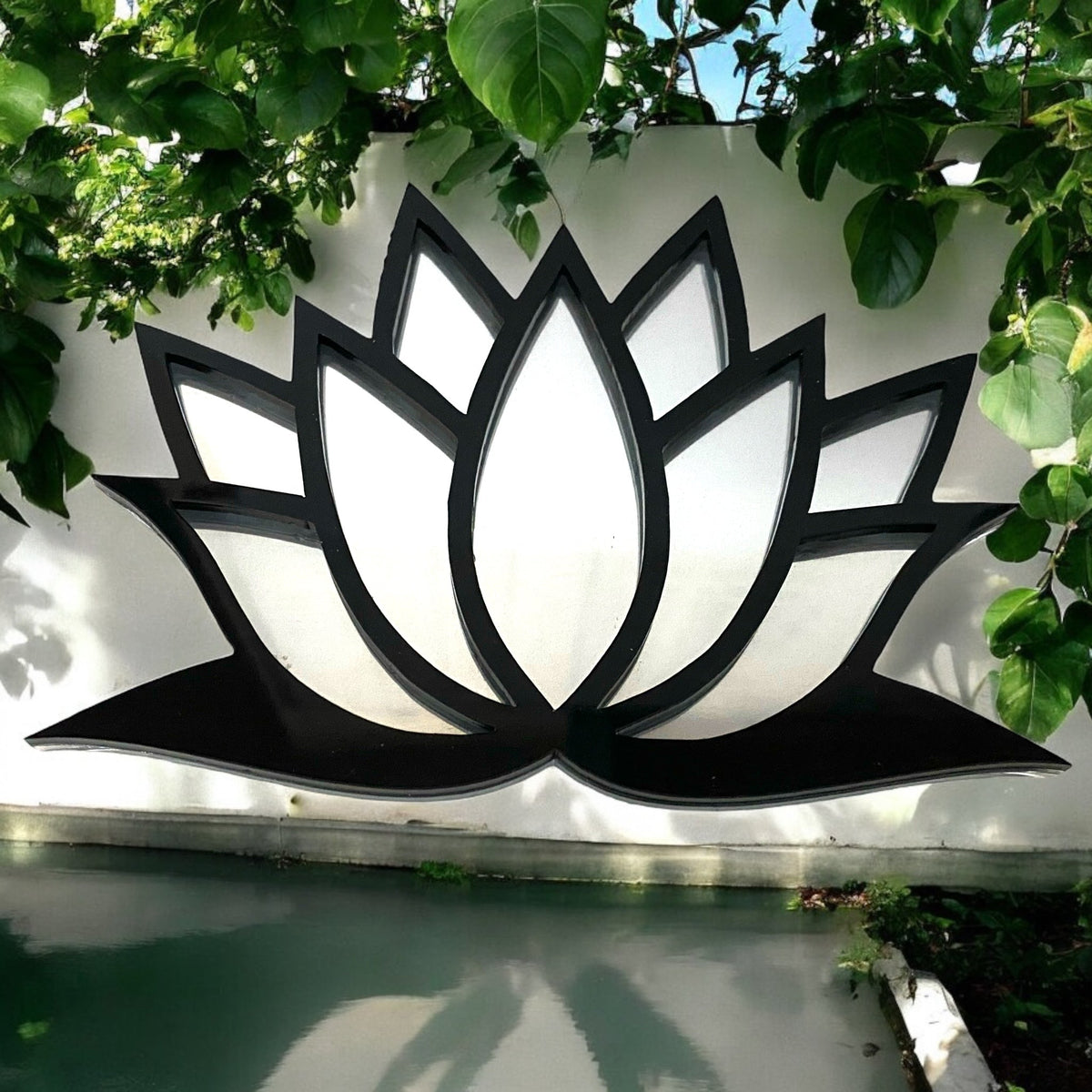 Black-framed lotus flower garden mirror hanging on a white wall above water.