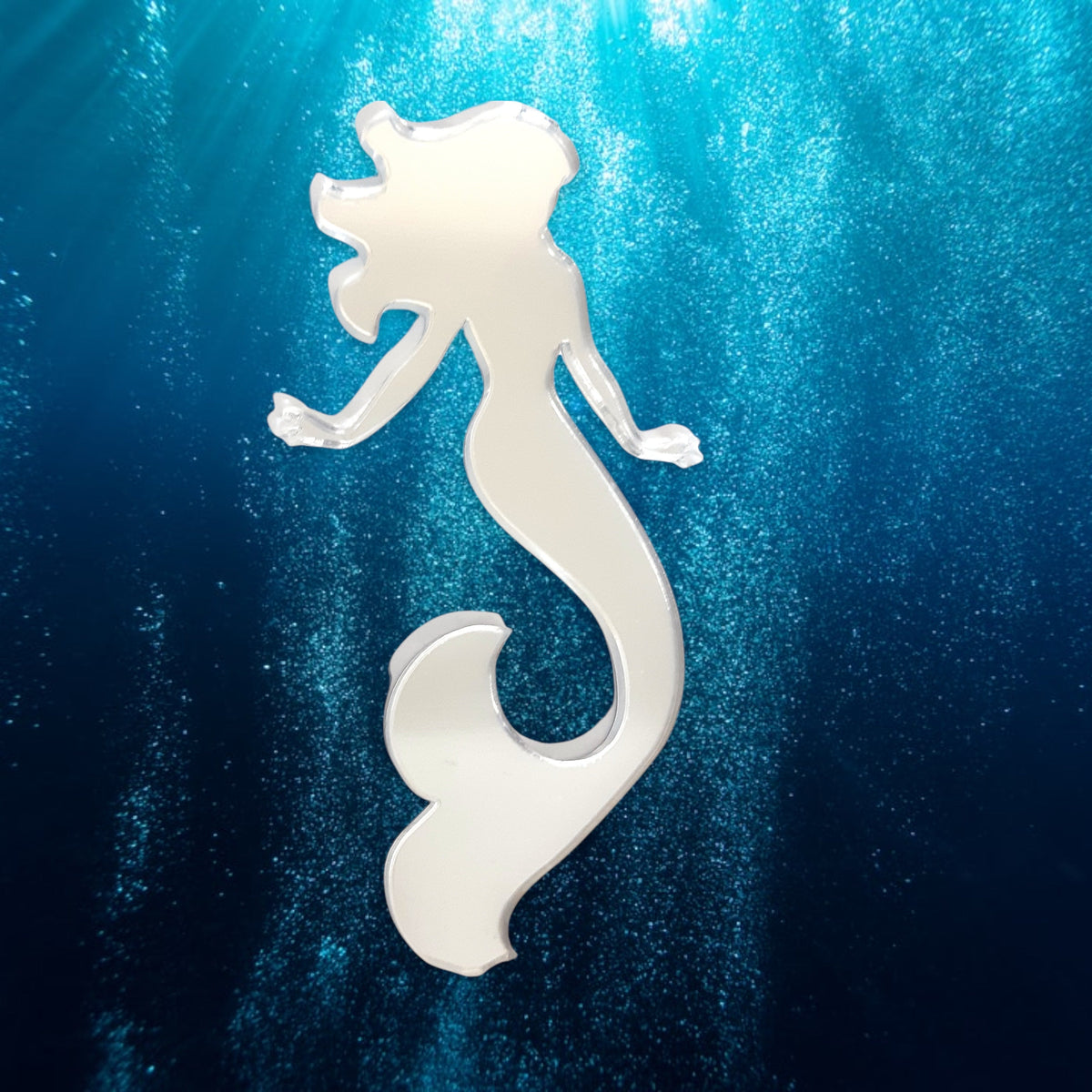 Mermaid-shaped acrylic mirror against a blue underwater background.