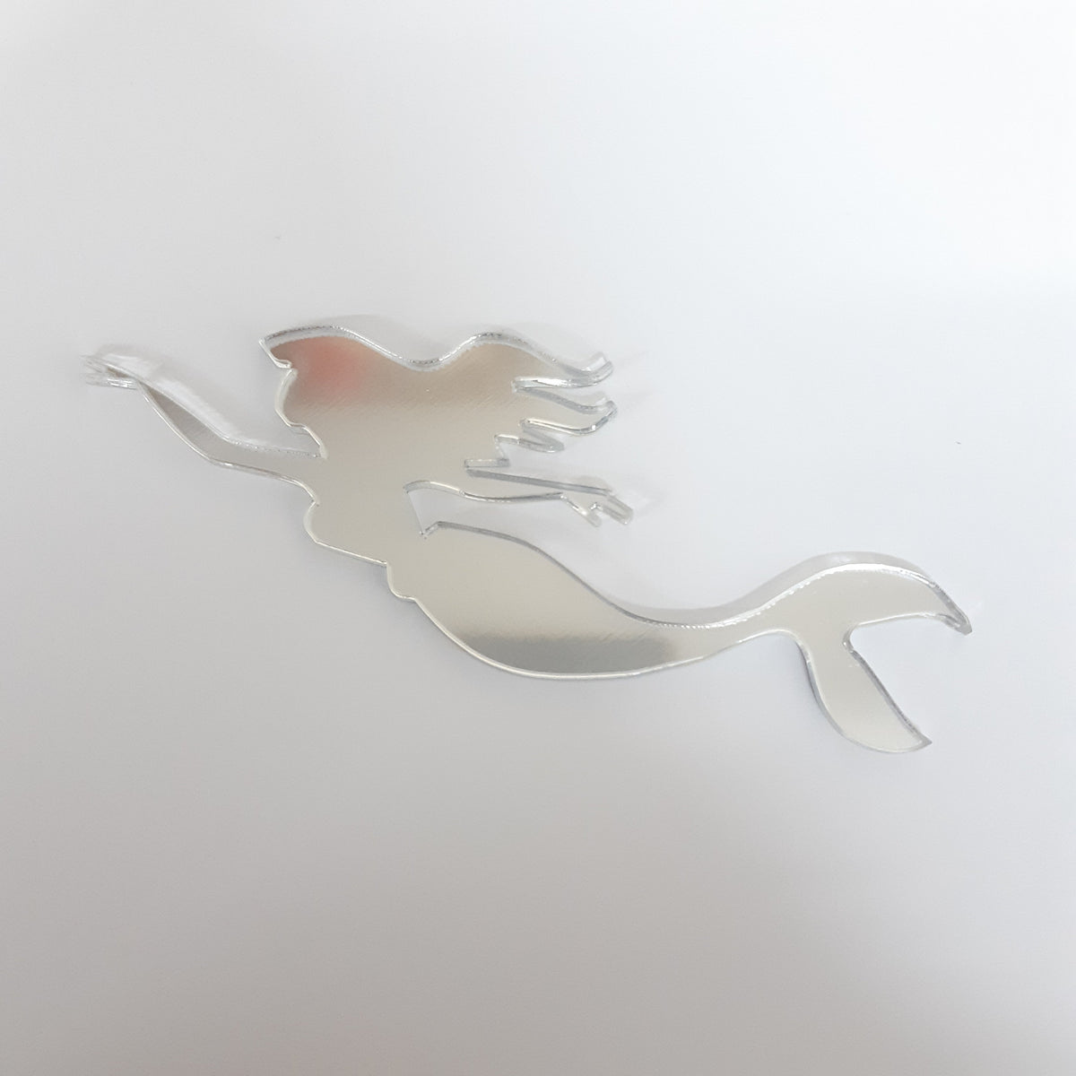 Silver reflective acrylic mirror in the shape of a swimming mermaid.