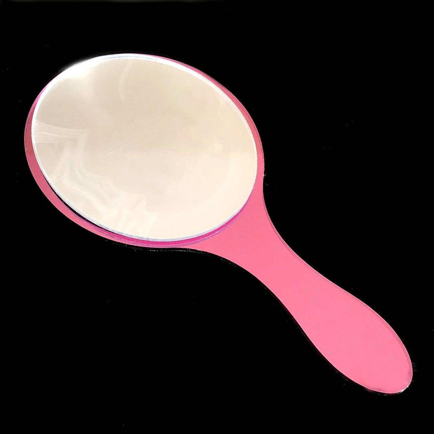 An oval pink hand-held mirror with a handle, isolated on a black background.