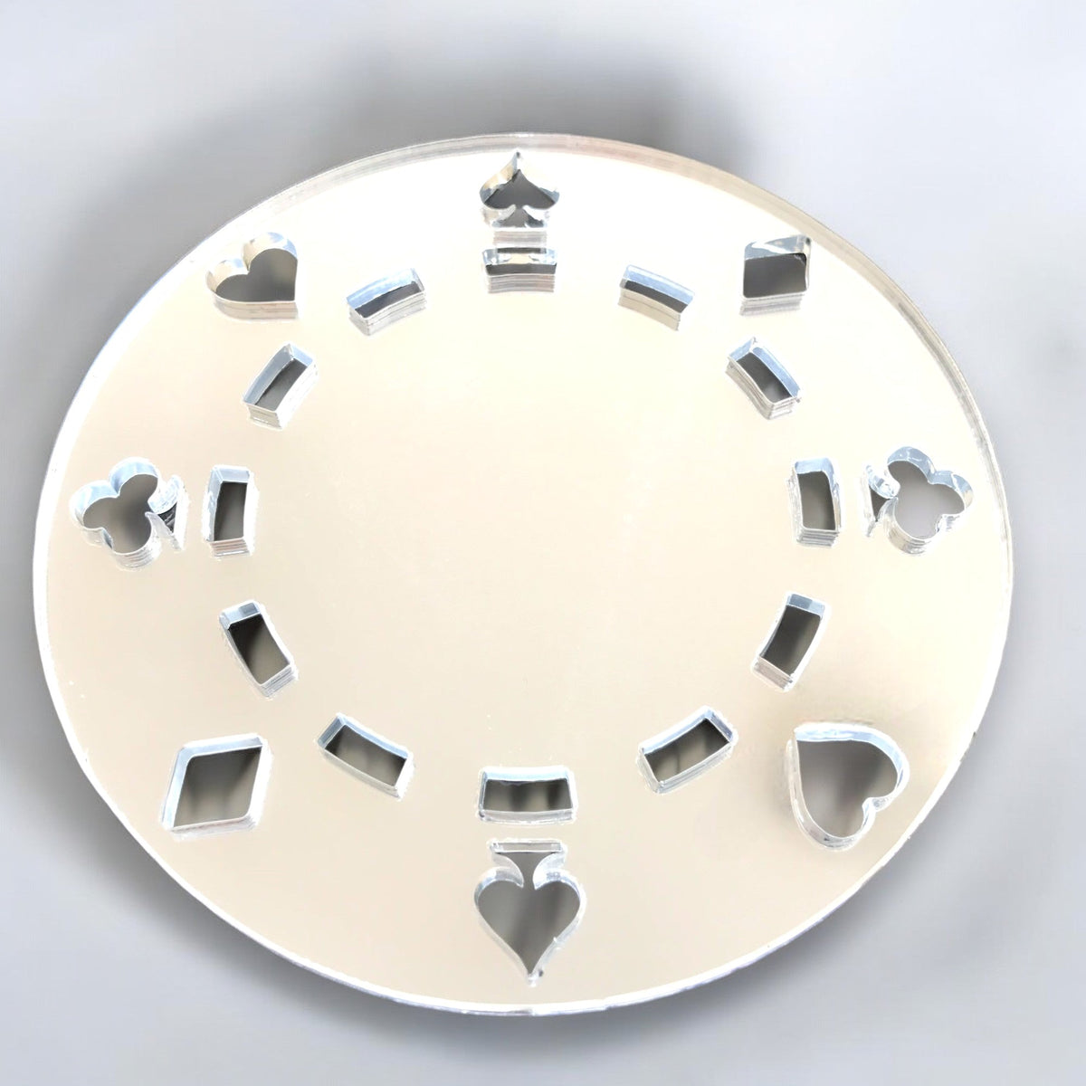 Round silver poker chip mirror with card suit cutouts arranged in a circle.