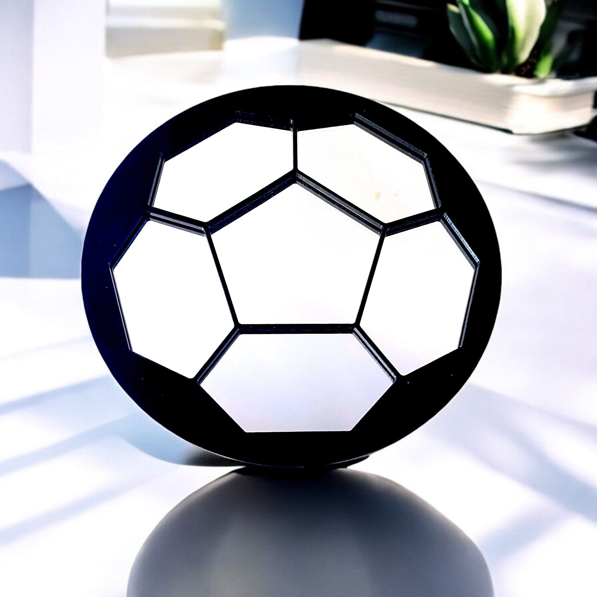 Round football-shaped mirror with black frame and hexagonal mirror panels on a stand.