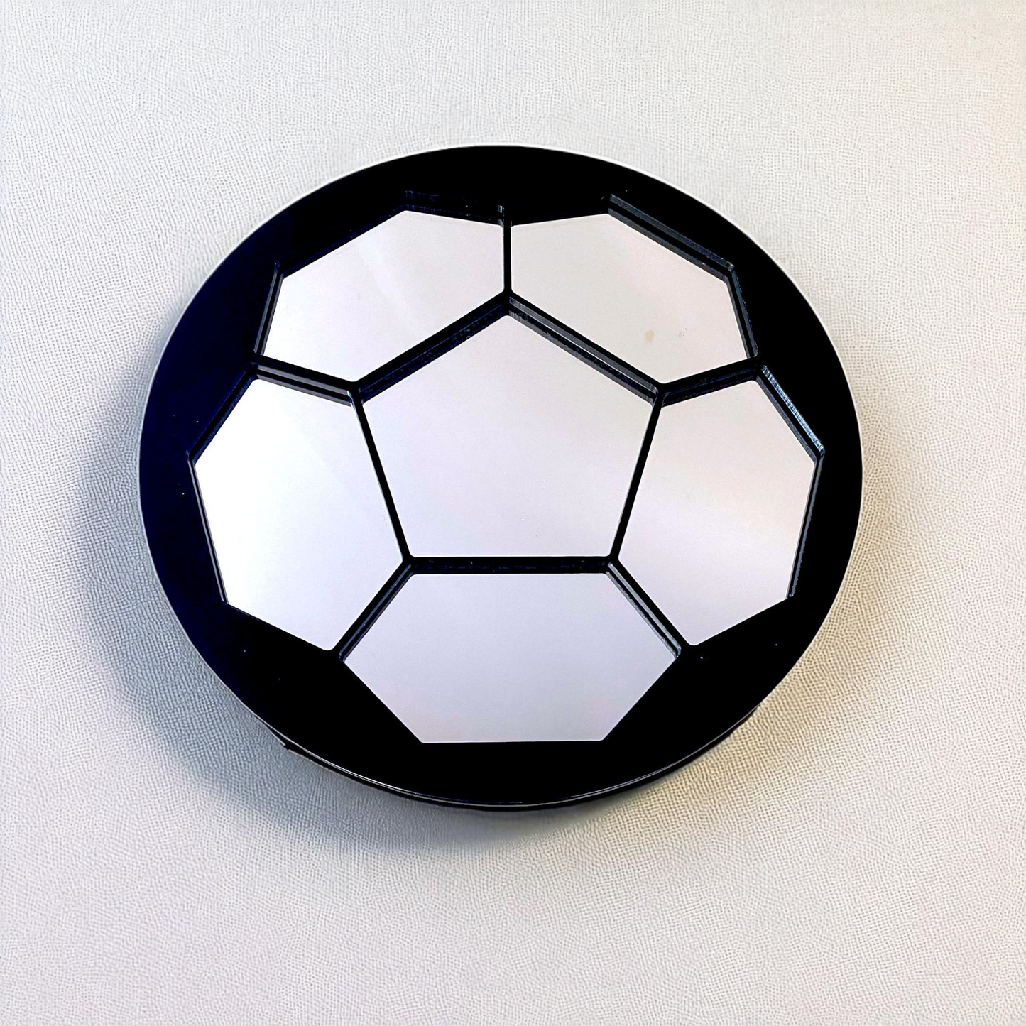 Round black-framed mirror shaped like a soccer ball with mirrored panels.
