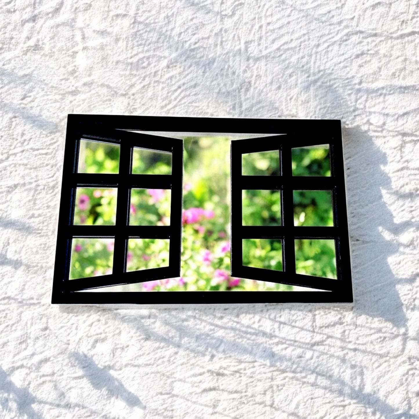 Rectangular black-framed window garden mirror mounted on a white textured wall.