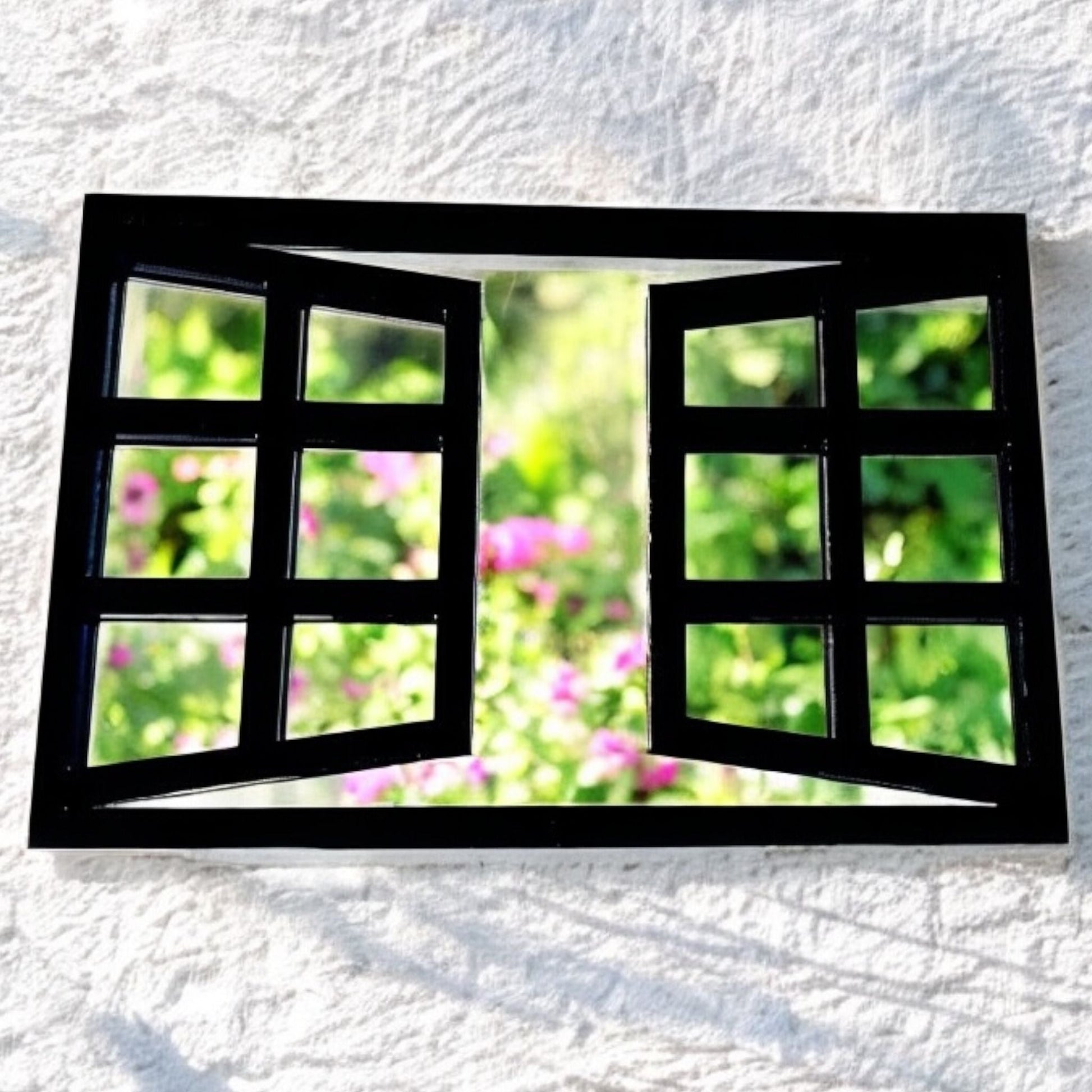 Rectangular black metal window garden mirror with open pane design mounted on white wall.