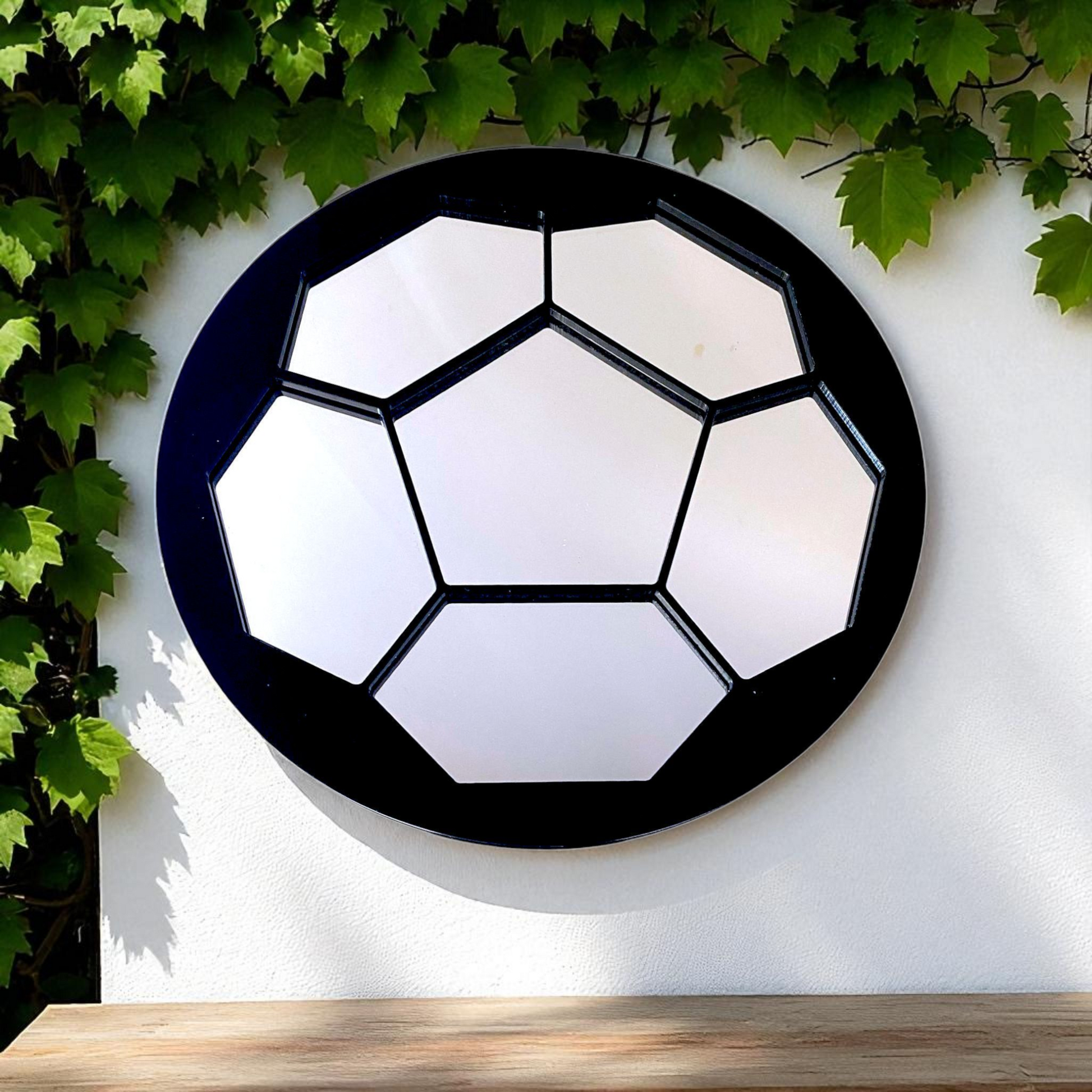 Round football garden mirror with mirrored pentagon and hexagon panels, set against a white wall.