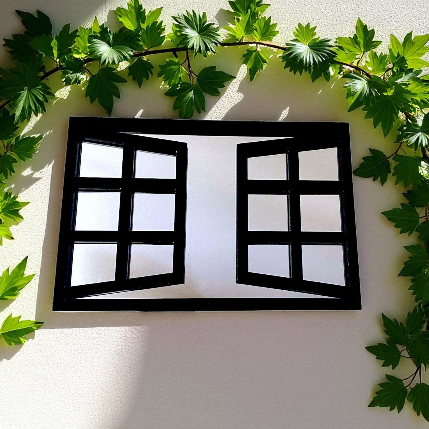 Rectangular black window-pane mirror hanging on a wall, surrounded by green ivy vines.