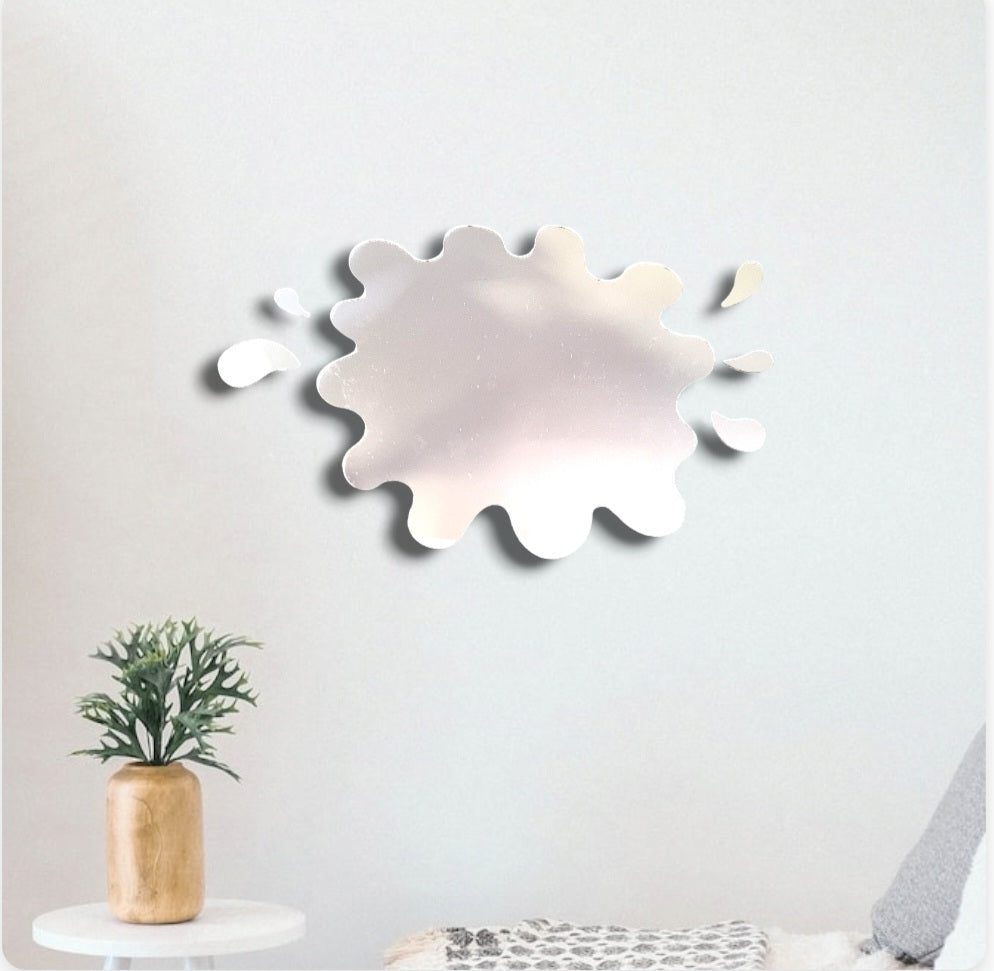 Puddle and six-splashes wall mirror mounted on a white wall above a small table with a potted plant.
