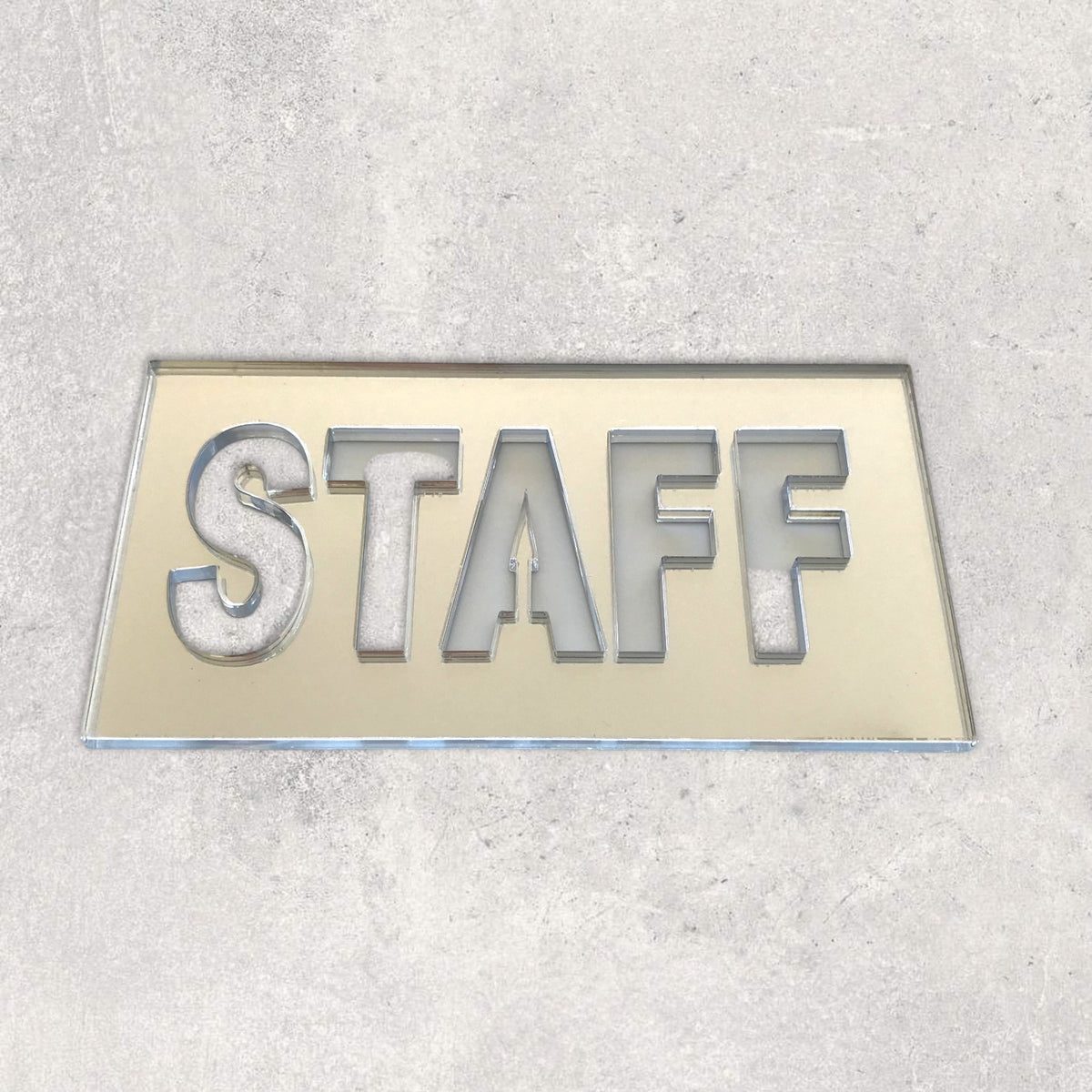 Rectangular reflective acrylic Staff sign with cut-out block letters, placed on a light grey surface.