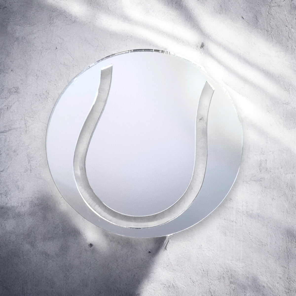 A circular tennis ball-shaped mirror on a textured gray wall.