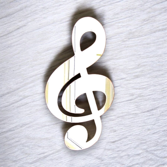 Treble clef shaped mirror on a light wood-grain background.