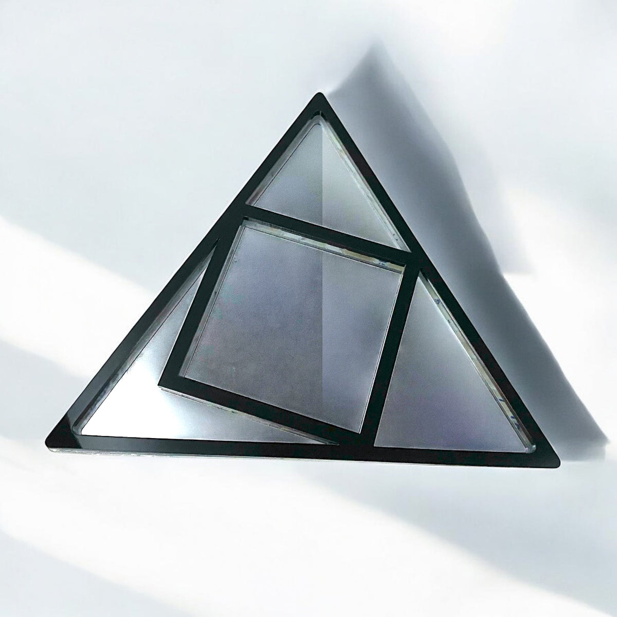 Black-framed triangular garden mirror featuring an internal square section, creating geometric mirrored panes.