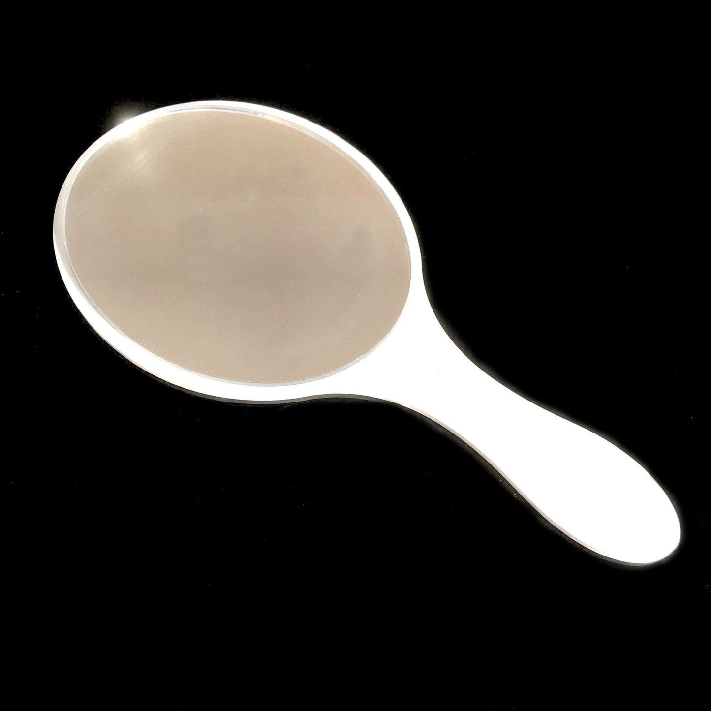 Oval hand-held mirror with a glossy white handle against a black background.