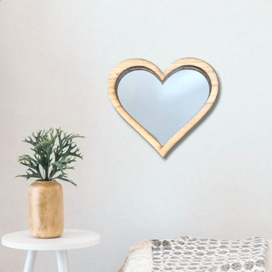 Heart-shaped mirror with a light wood frame hanging on a white wall.