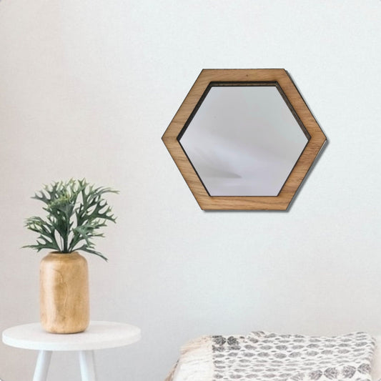Hexagonal mirror with light brown wood frame hanging on a white wall.