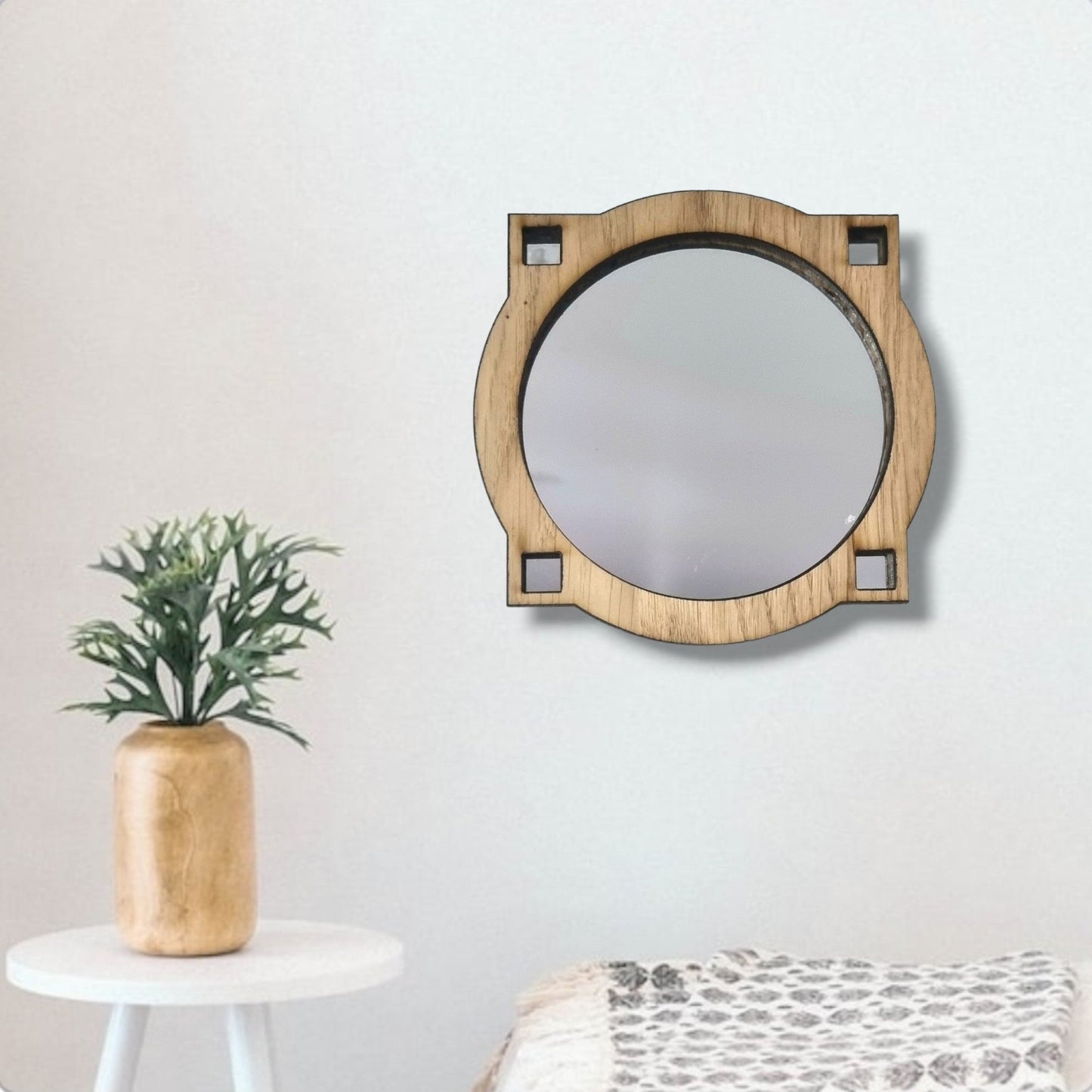Art deco style round mirror with a wooden geometric frame hanging on a white wall.