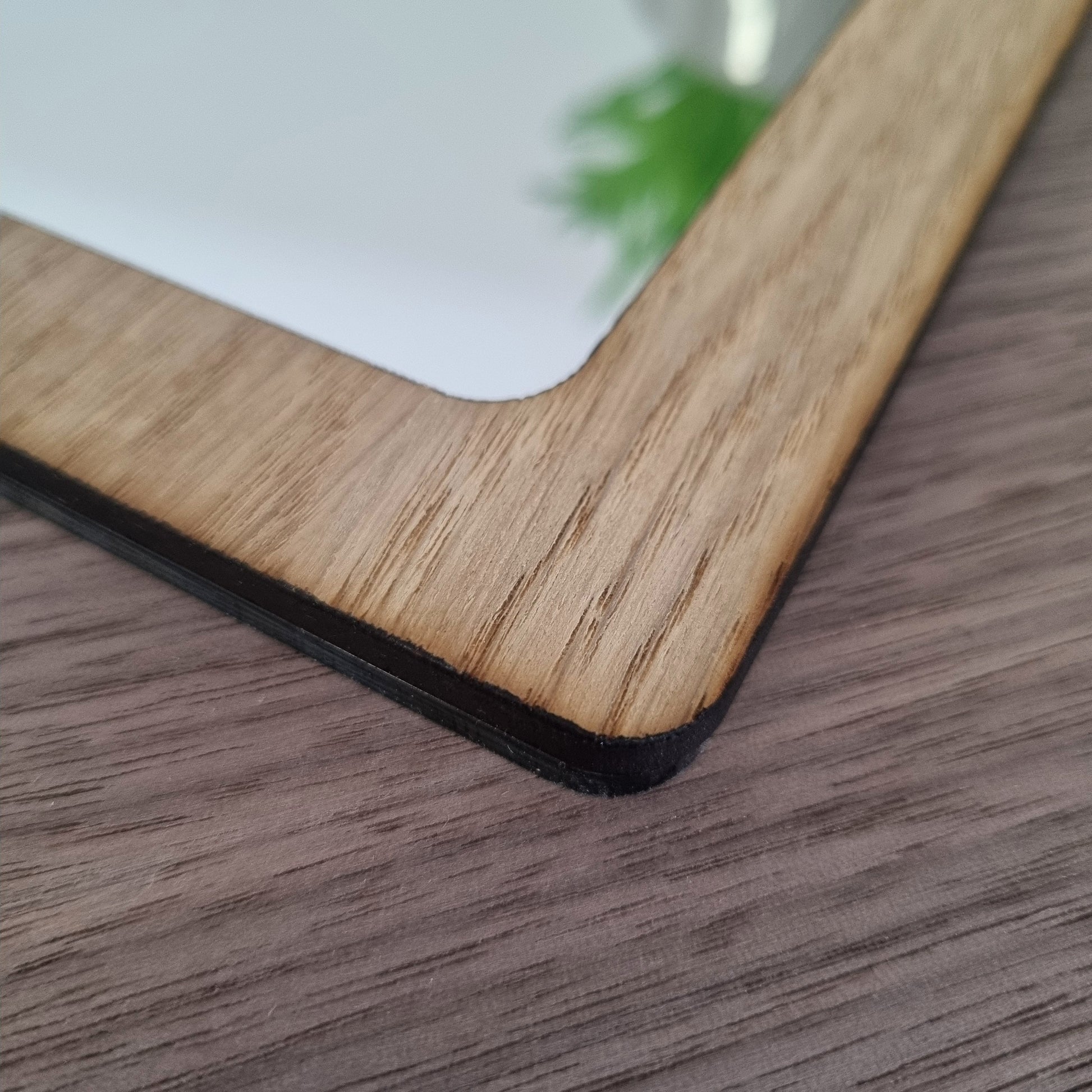 Close-up of a rectangular mirror with a light brown wood grain frame.