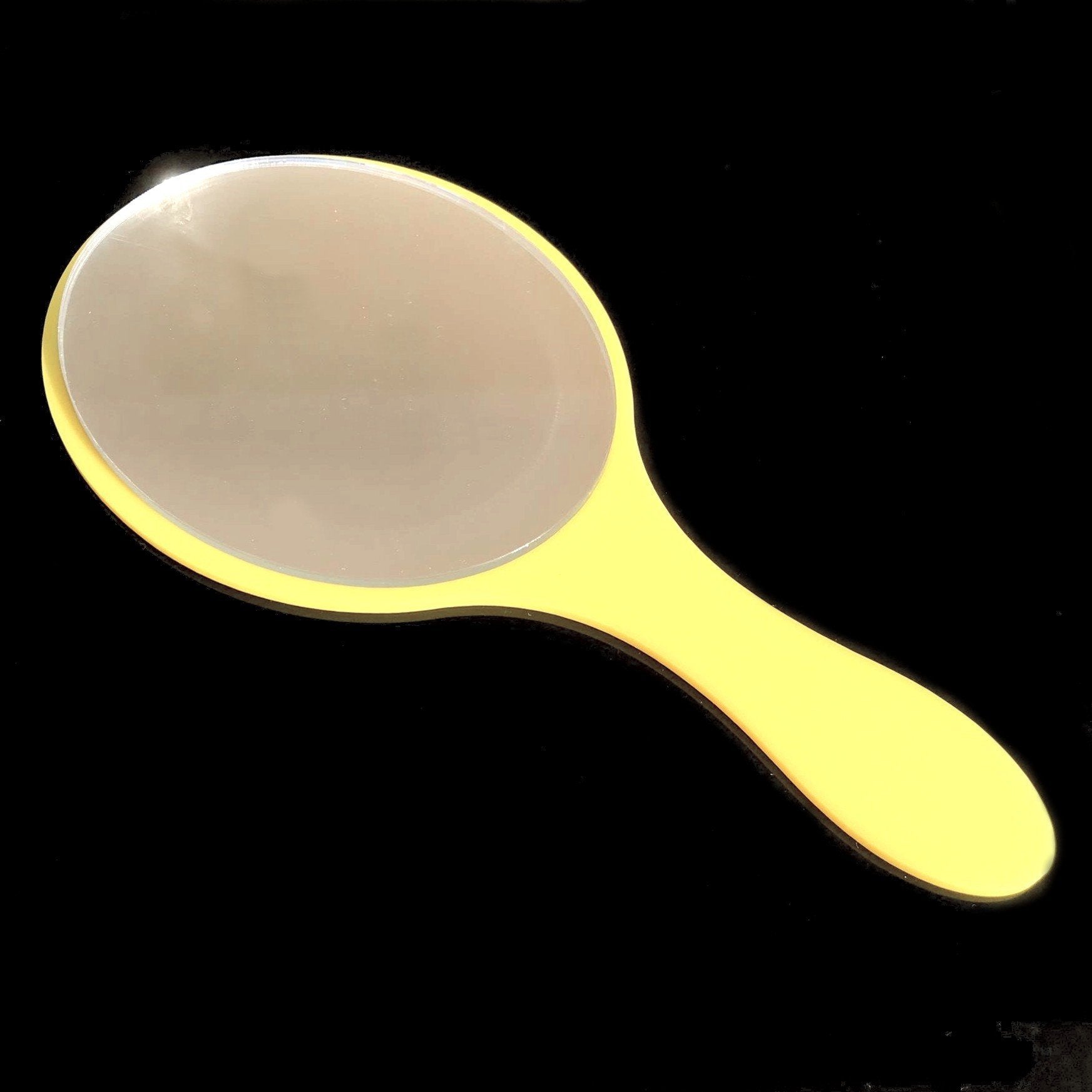 An oval hand-held mirror with a glossy yellow handle on a black background.